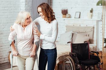 Pflegekraft bügelt für einen älteren Mann